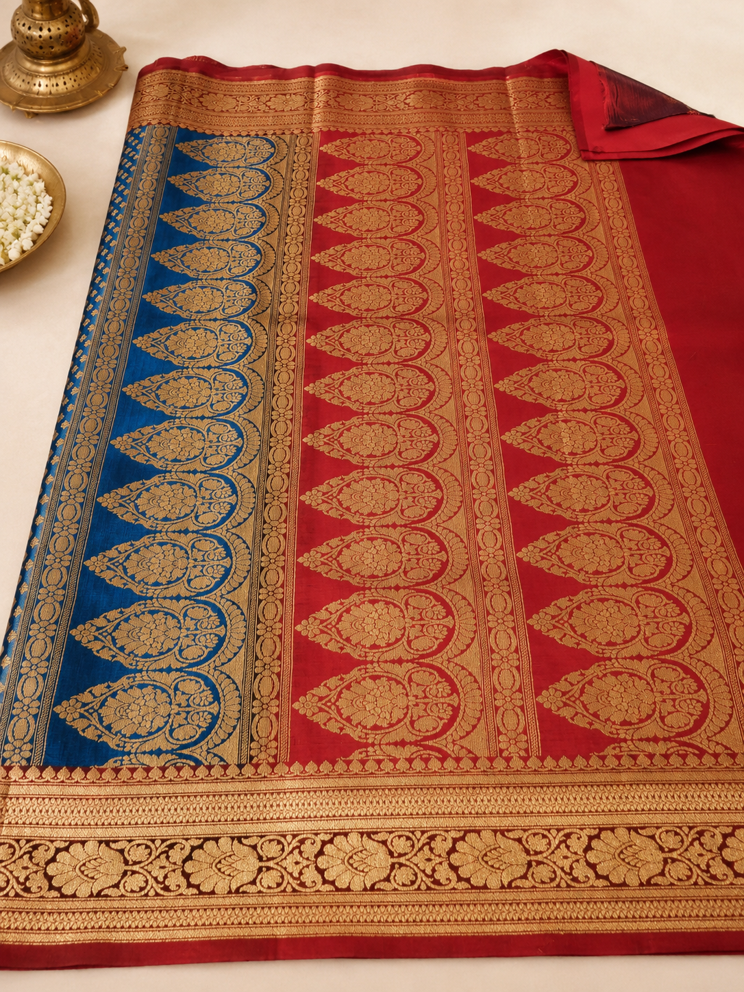 Teal blue Banarasi silk saree – full open flat lay showing teal body with gold booti, red contrast pallu with large gold woven paisley motifs