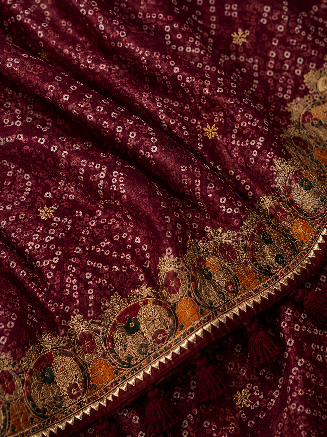 Maroon bandhani georgette saree – fabric close-up showing dense bandhani dot pattern, gold star motifs and embroidered gold medallion border