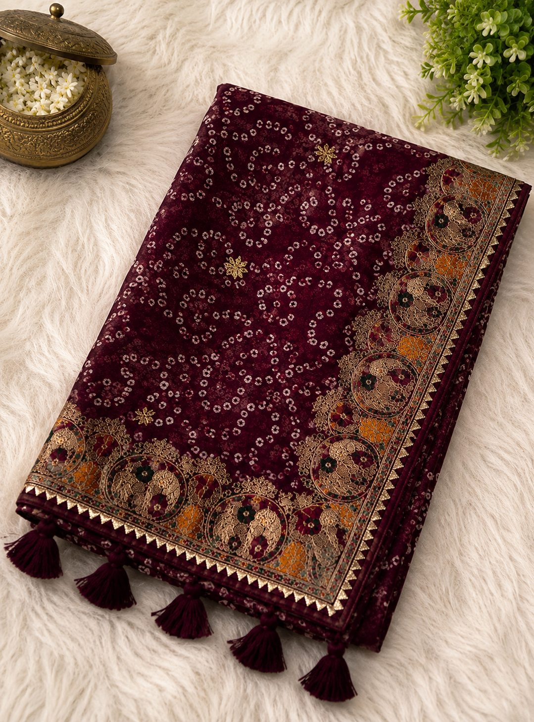 Maroon bandhani georgette saree – folded view showing all-over bandhani pattern, wide gold medallion border and maroon tassels