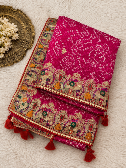 Rani pink bandhani georgette saree – folded flat lay showing all-over bandhani pattern, wide paisley border and red tassels