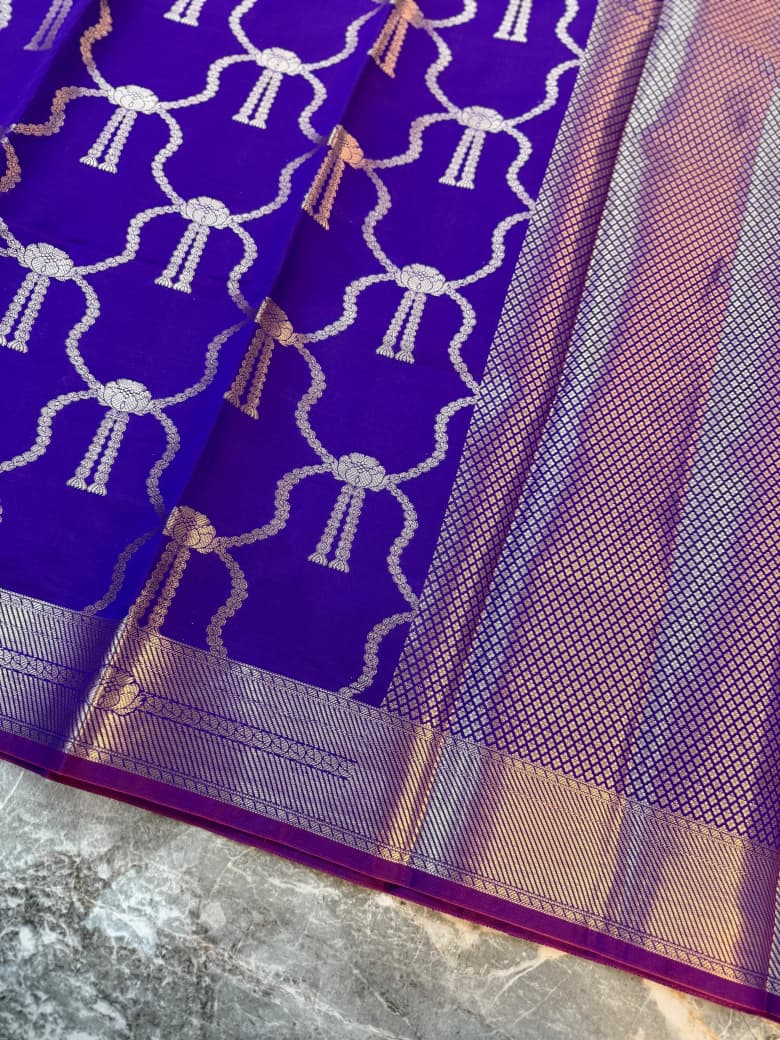 Close-up of purple Katan Banarasi saree showing repeating bow motifs, woven lattice pallu and zari border