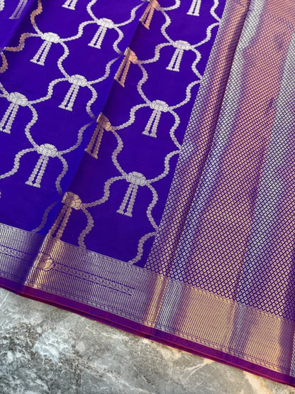 Close-up of purple Katan Banarasi saree showing repeating bow motifs, woven lattice pallu and zari border