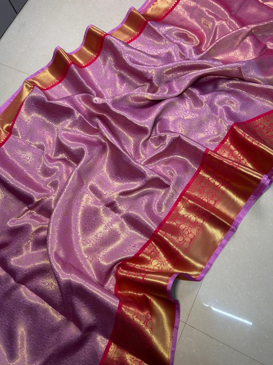 Lavender pink Katan Banarasi saree spread out showing its broad wine-gold zari border and geometric pallu